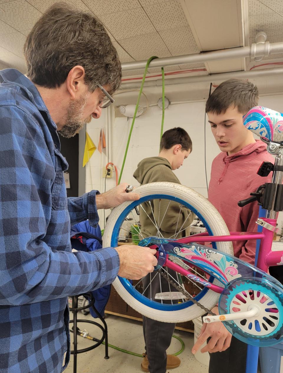 Mechanic Dan Rosenburg shows students how to repair a donated bike to those in need.