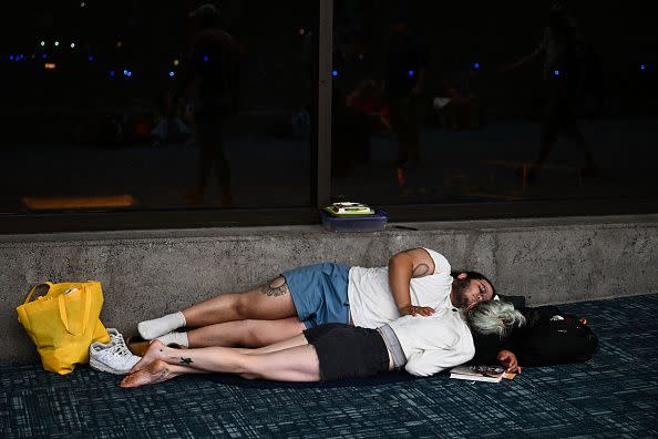 Passengers try to sleep on the floor of the airport terminal while waiting for delayed and canceled flights off the island as thousands of passengers were stranded at the Kahului Airport (OGG) in the aftermath of wildfires in western Maui in Kahului, Hawaii on August 9, 2023. The death toll from a wildfire that turned a historic Hawaiian town to ashes has risen to 36 people, officials said on August 9. (Photo by Patrick T. Fallon / AFP) (Photo by PATRICK T. FALLON/AFP via Getty Images)