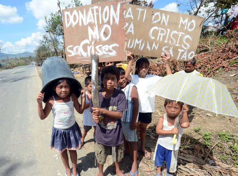 Children beg for alms on a roadside in the town of Osmena in Compostela Valley province on Sunday. Desperate families begged for food, days after a typhoon brought death and destruction to parts of a southern Philippine island, as the storm returned to the north of the country