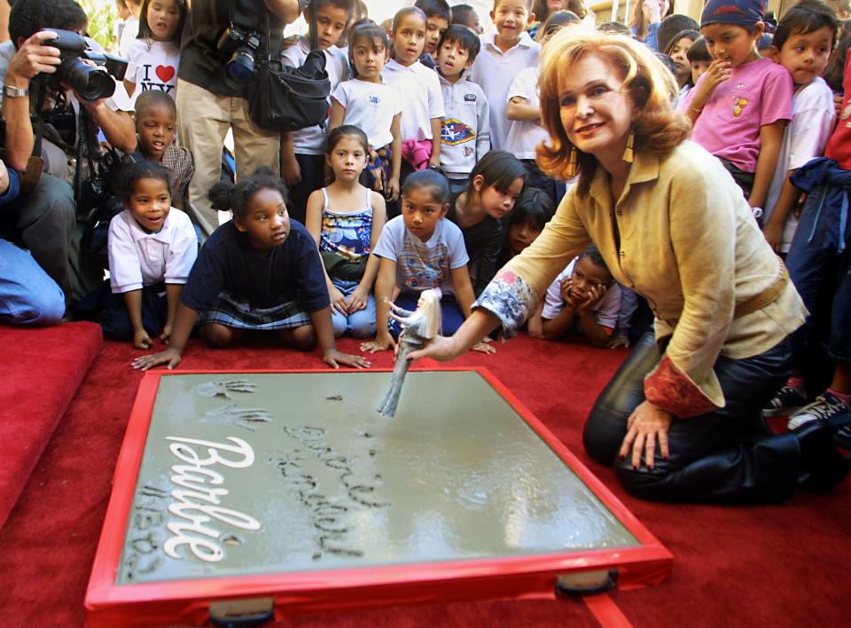 Barbara Handler Segal, whose mother, Ruth Handler, created and named the Barbie doll after her, is surrounded by school children during a ceremony in which her hand and footprints were placed in wet cement in front of the Egyptian Theatre on Hollywood Boulevard Nov. 13, 2002.
