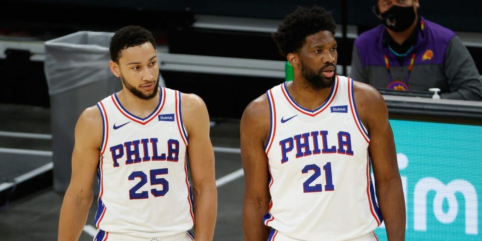 Ben Simmons stands next to Joel Embiid during a game.