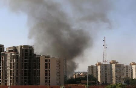 Smoke rises near buildings after heavy fighting between rival militias broke out near the airport in Tripoli July 13, 2014. REUTERS/ Hani Amara