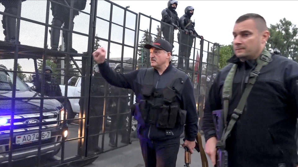 Image: Belarus President Alexander Lukashenko armed with a Kalashnikov-type rifle greeting riot police officers near the Palace of Independence in Minsk (State TV and Radio Company of Belarus via AP / AP)