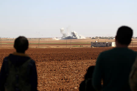 Rebel fighters look towards rising smoke from airstrikes on Guzhe village, northern Aleppo countryside, Syria October 17, 2016. REUTERS/Khalil Ashawi