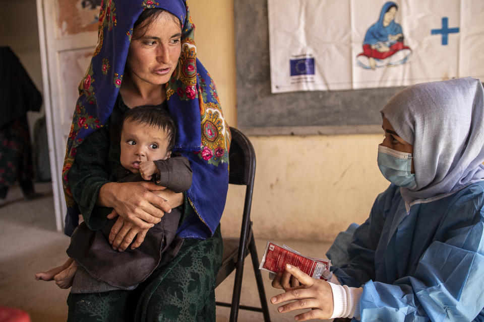 File - A Save the Children nutrition counsellor, right, explains to Nelab, 22, how to feed her 11-month-old daughter, Parsto, with therapeutic food, which is used to treat severe acute malnutrition, in Sar-e-Pul province of Afghanistan, Thursday, Sept. 29, 2022. (Save the Children via AP, File)