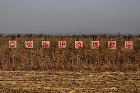 A sign reading, "Take the initiative to preserve order along the border," stands in a field at the border between China and North Korea just outside Dandong, Liaoning province, China, November 19, 2017. A week-long road trip along China's side of its border with North Korea showed places where it is porous. REUTERS/Damir Sagolj