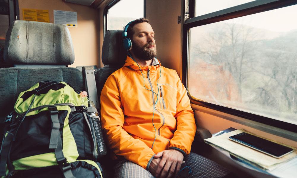 Young man with headphones napping in the train