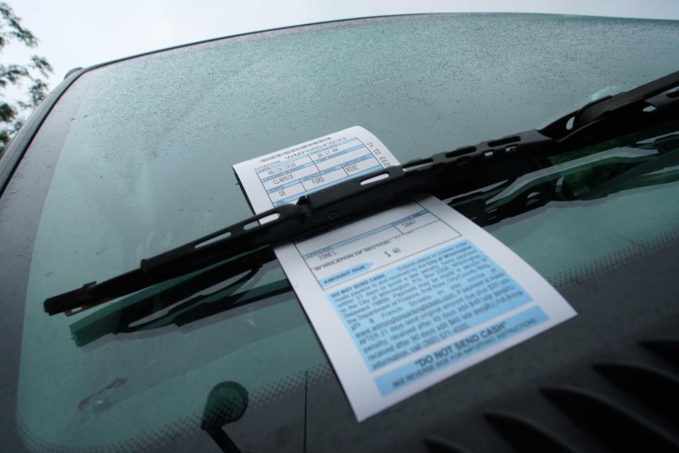 A vehicle along Market Street sits with a City of Wilmington parking ticket under the windshield wiper.