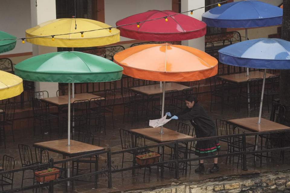 A worker dries tables at restaurant on the River Walk after a light rain, Tuesday, Jan. 23, 2024, in San Antonio. (AP Photo/Eric Gay)