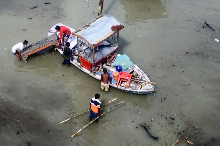 Flood-affected residents move their belongings on a boat following heavy monsoon rains in the Indian city of Prayagraj (Sanjay KANOJIA)