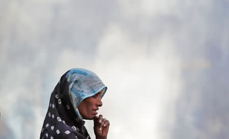 A woman stands next to the burning pyre of a family member who died after a commuter train traveling at high speed ran through a crowd of people on the rail tracks on Friday, at a cremation ground in Amritsar, India, October 20, 2018. REUTERS/Adnan Abidi