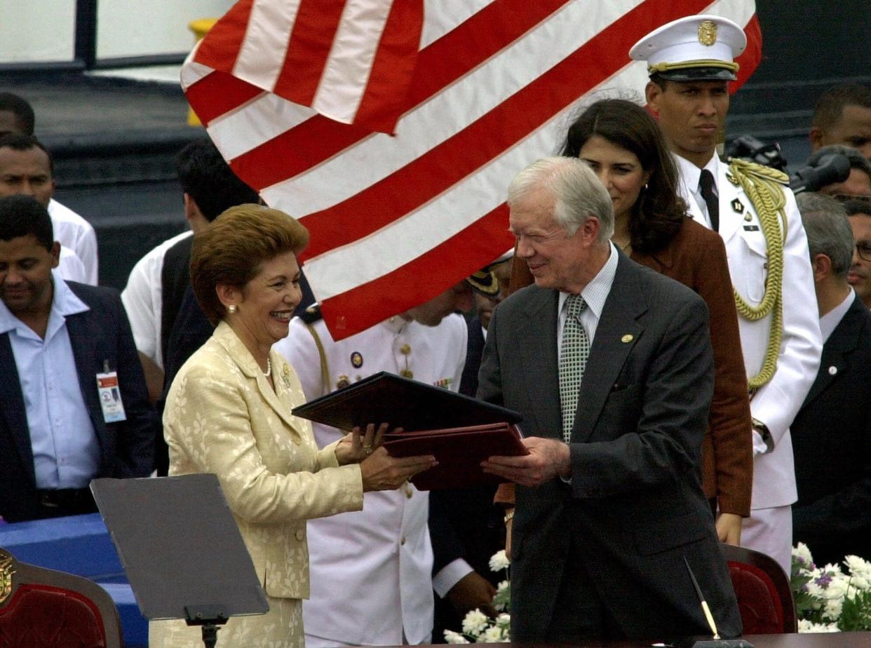 Former President Jimmy Carter, right, exchanges documents with Panamanian President Mireya Moscoso during a ceremony to transfer control of the Panama Canal to Panama after 85 years of American control on Dec. 14, 1999, outside of Panama City. Panama will fully take control of the Panama Canal on December 31.