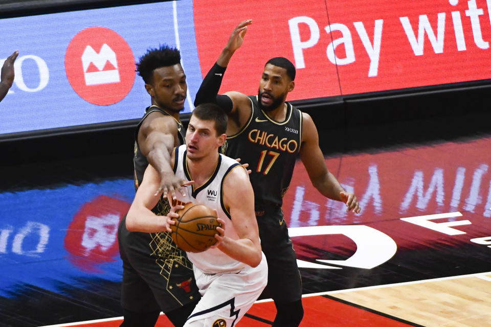 Denver Nuggets center Nikola Jokic, center, moves the ball away from Chicago Bulls center Wendell Carter Jr., left, and Garrett Temple (17) during the first half of an NBA basketball game Monday, March 1, 2021, in Chicago. (AP Photo/Matt Marton)