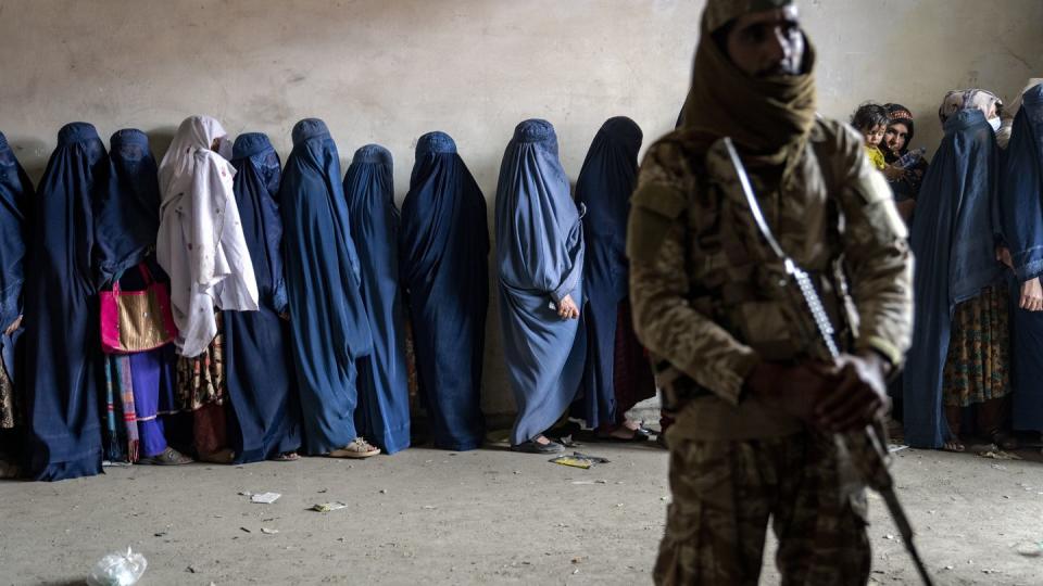 FILE - A Taliban fighter stands guard as women wait to receive food rations distributed by a humanitarian aid group in Kabul, Afghanistan, Tuesday, May 23, 2023. (Ebrahim Noroozi/AP, File)