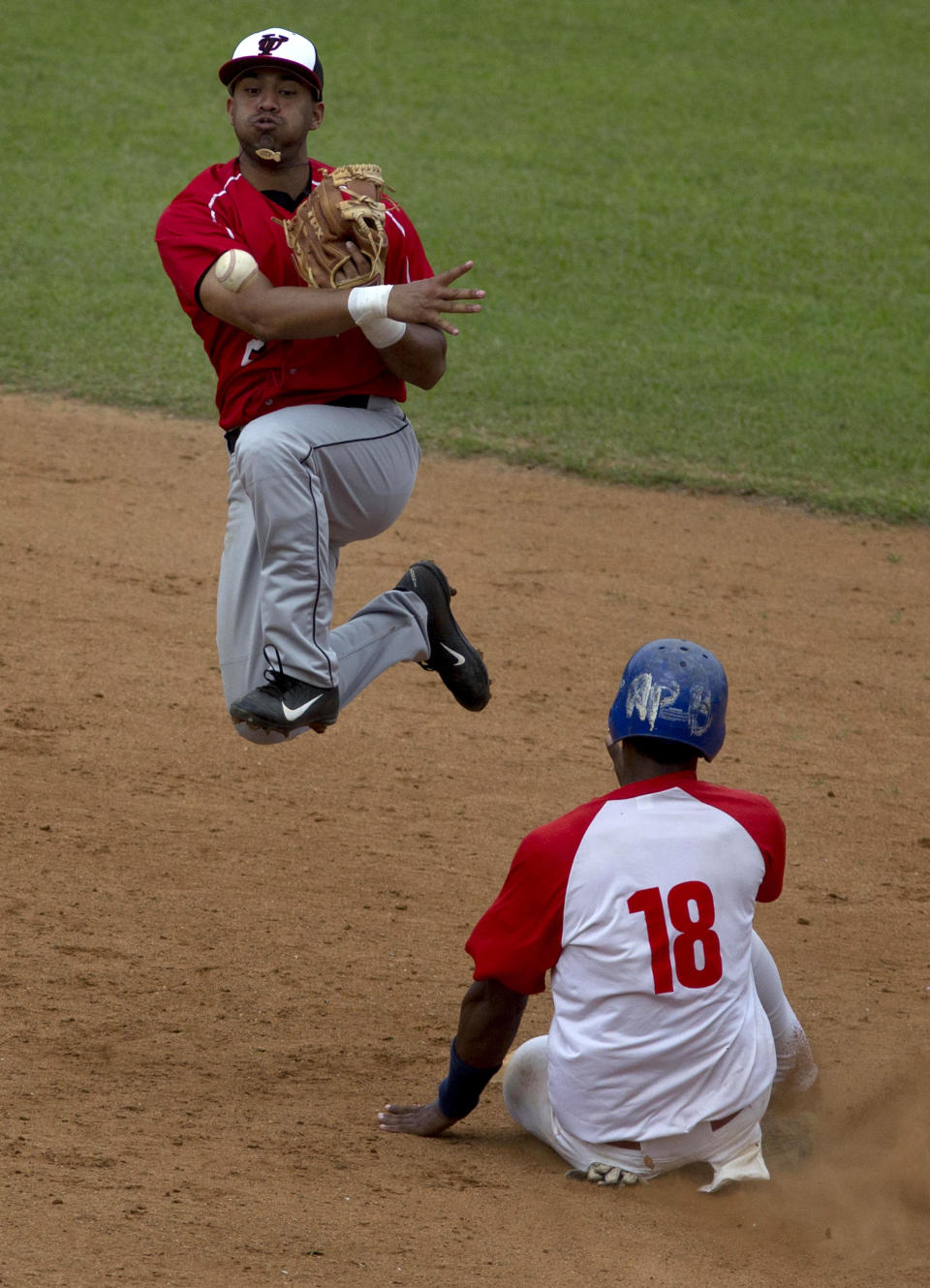 A player from the University of Tampa, left, outs a player from a Cuban youth team at second and throws to first during an exhibition game in Havana, Cuba, Wednesday, Jan. 15, 2014. Cultural exchanges between Cuba and the U.S. have become increasingly common in recent years. President Barack Obama's administration has restored so-called people-to-people tours, resulting in tens of thousands of Americans visiting the island each year legally. (AP Photo/Ramon Espinosa)