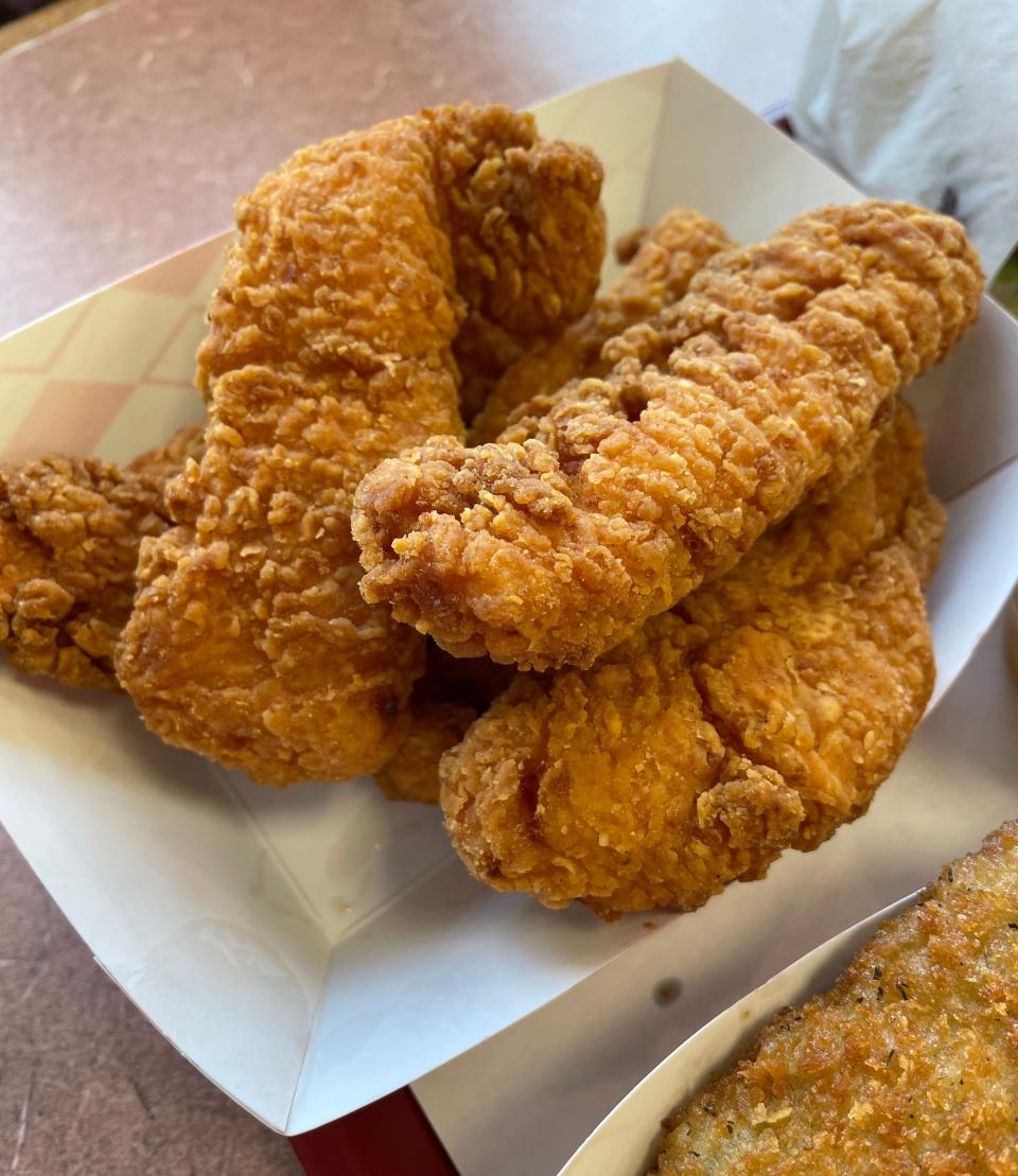 The chicken tenders have a crispy exterior with a juicy white meat center, and come with a side of dipping sauce.