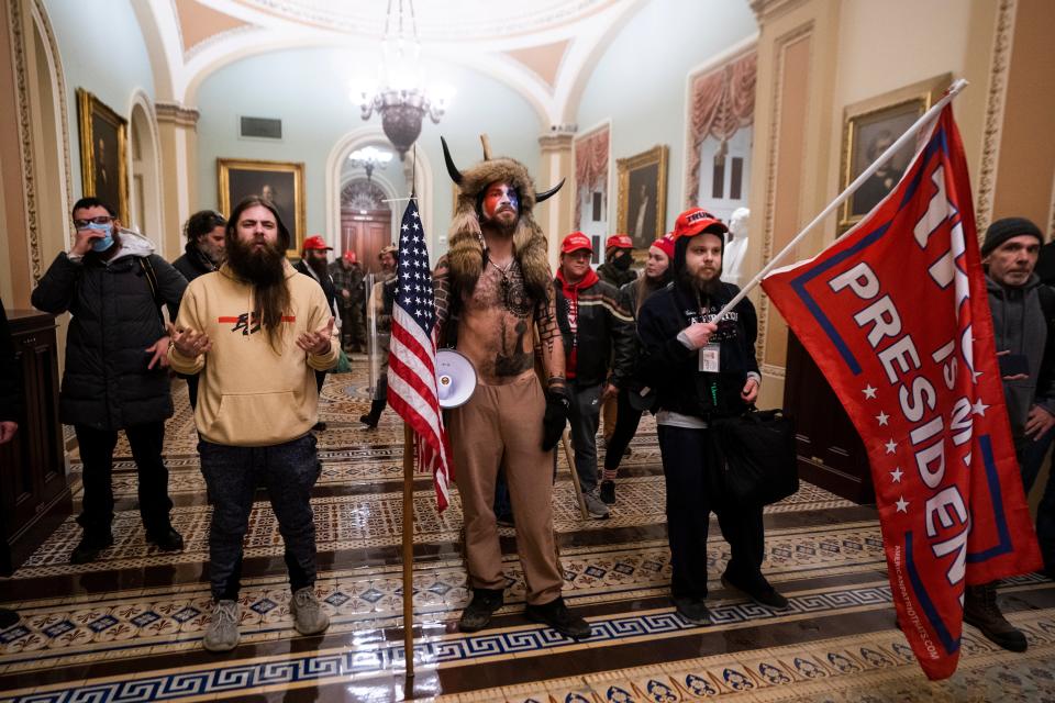 Jake Angeli, center, stands in the US Capitol dressed in fur and horns after Trump supporters stormed the building on 6 January in an effort to force legislators to overturn the election results.EPA