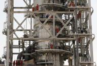 In this photo opportunity during a trip organized by Saudi information ministry, workers fix the damage in the Aramco's Khurais oil field, Saudi Arabia, Friday, Sept. 20, 2019, after it was hit during Sept. 14 attack. Saudi officials brought journalists Friday to see the damage done in an attack the U.S. alleges Iran carried out. (AP Photo/Amr Nabil)