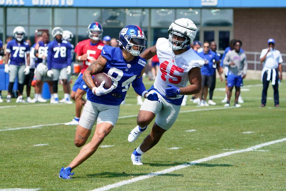 New York Giants rookie wide receiver Jalin Hyatt (84) runs with the ball with pressure from rookie linebacker Habakkuk Baldonado (45) on the first day of training camp in East Rutherford on Wednesday, July 26, 2023.