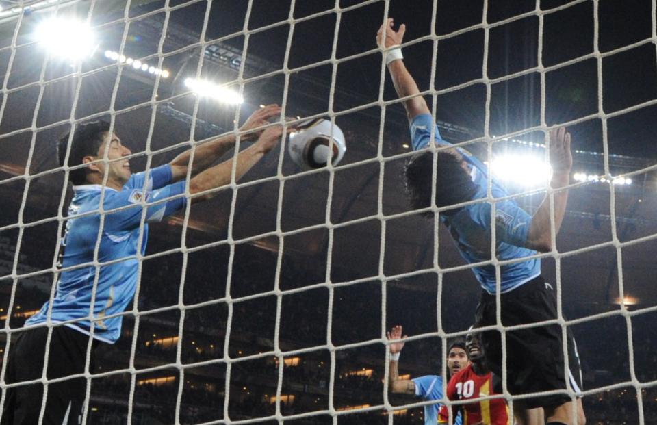 Uruguay's striker Luis Suarez (L) stops the ball with the hand leading to a red card and a penalty for Ghana during the extra-time of 2010 World Cup quarter-final match Uruguay vs. Ghana on July 2, 2010 at AFP Soccer City stadium in Soweto, suburban Johannesburg.  NO PUSH TO MOBILE / MOBILE USE SOLELY WITHIN EDITORIAL ARTICLE  -  AFP PHOTO / ROBERTO SCHMIDT (Photo credit should read ROBERTO SCHMIDT/AFP via Getty Images)