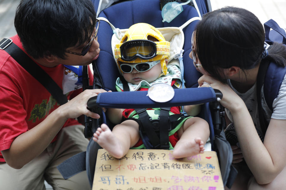 A couple tends to their child as they take part in a protest in Hong Kong on Saturday, Aug. 10, 2019. China's central government has dismissed Hong Kong pro-democracy protesters as clowns and criminals while bemoaning growing violence surrounding the monthslong demonstrations. (AP Photo/Vincent Thian)