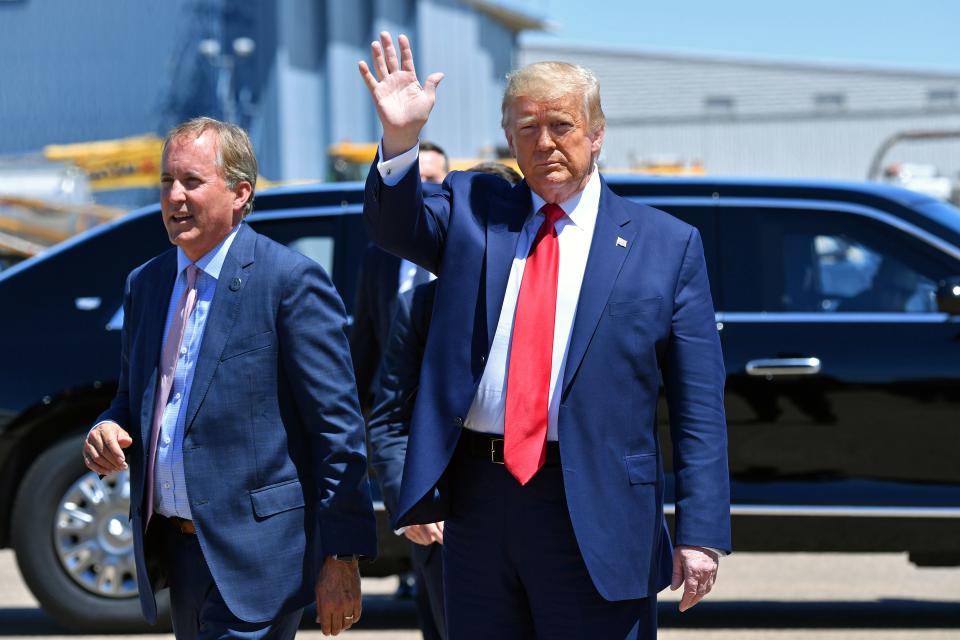 Donald Trump waves as he stands next to Paxton outdoors in Dallas.