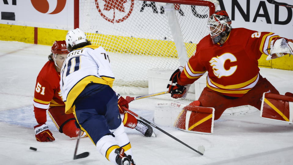 Nashville Predators forward Egor Afanasyev, center, scores as Calgary Flames defenseman Troy Stecher, left, and goalie Jacob Markstrom try to stop him during the first period of an NHL hockey game in Calgary, Alberta, Monday, April 10, 2023. (Jeff McIntosh/The Canadian Press via AP)