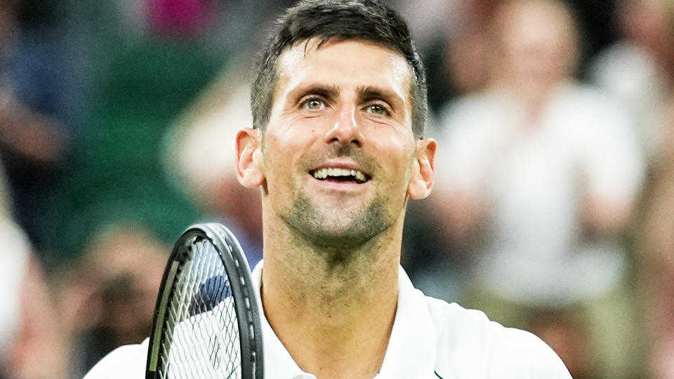 Novak Djokovic is pictured smiling to the crowd at Wimbledon 2022.