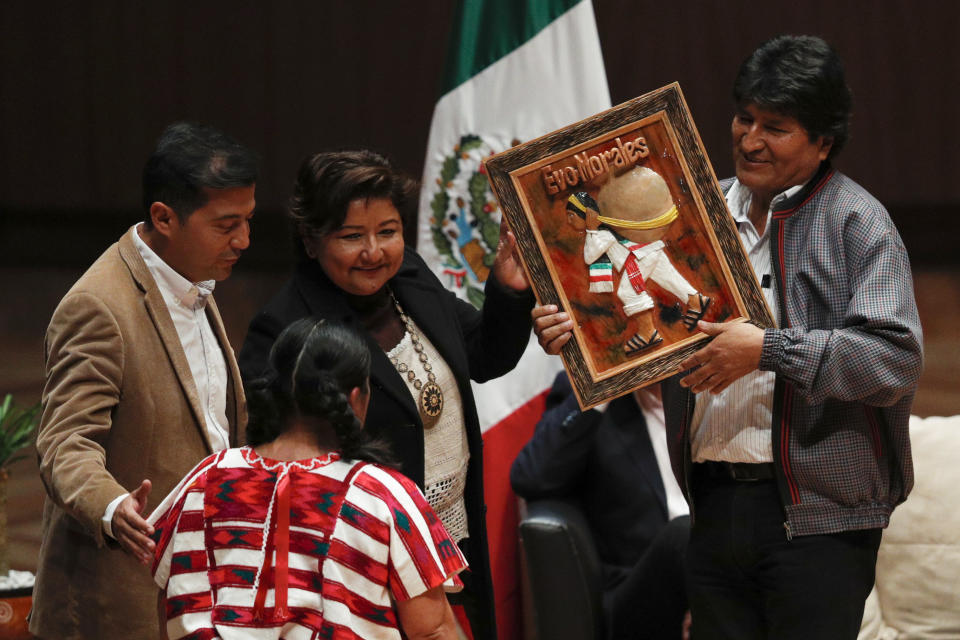 Members of an indigenous community present Bolivia's former President Evo Morales, right, with an artwork during a dialog with students and indigenous communities, at Ollin Yoliztli Cultural Center in Mexico City, Tuesday, Nov. 26, 2019. Bolivia is struggling to stabilize after weeks of anti-government protests and violence in which at least 30 people have been killed. Former president Evo Morales resigned on Nov. 10 after an election that the opposition said was rigged. (AP Photo/Rebecca Blackwell)