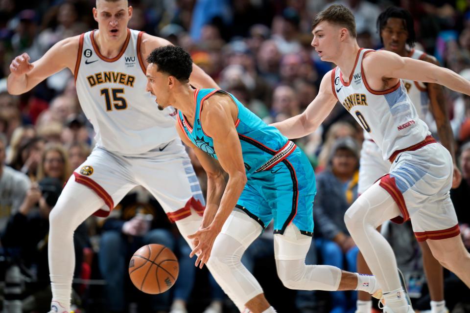 Phoenix Suns guard Landry Shamet, front, chases down a loose ball as Denver Nuggets center Nikola Jokic, back left, and guard Christian Braun defend in the first half of an NBA basketball game, Sunday, Dec. 25, 2022, in Denver. (AP Photo/David Zalubowski)