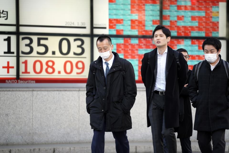 People walk in front of an electronic stock board showing Japan's Nikkei 225 index at a securities firm Tuesday, Jan. 30, 2024, in Tokyo. Asian shares were mixed on Tuesday, with Hong Kong and Shanghai leading declines, ahead of a decision by the Federal Reserve this week on interest rates. (AP Photo/Eugene Hoshiko)