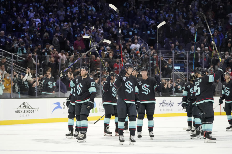 Seattle Kraken players raise their sticks after they beat the Montreal Canadiens 5-1 in an NHL hockey game, Tuesday, Oct. 26, 2021, in Seattle. (AP Photo/Ted S. Warren)