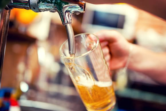 Hand holding glass under beer tap