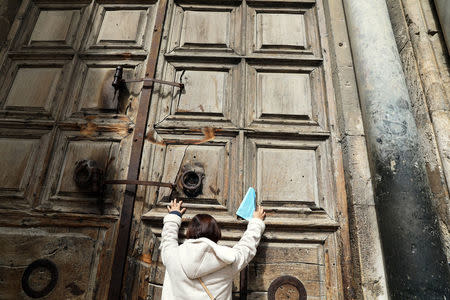 A worshipper touches the closed doors of the Church of the Holy Sepulchre in Jerusalem's Old City February 27, 2018. REUTERS/Ammar Awad