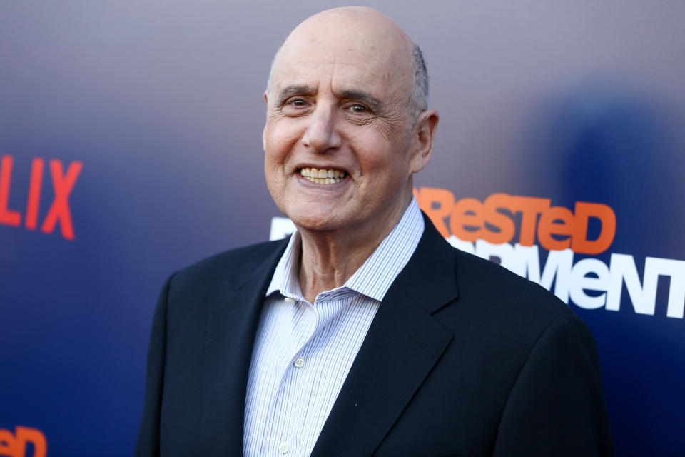 Jeffrey Tambor smiling at a Netflix event, dressed in a black suit and striped shirt