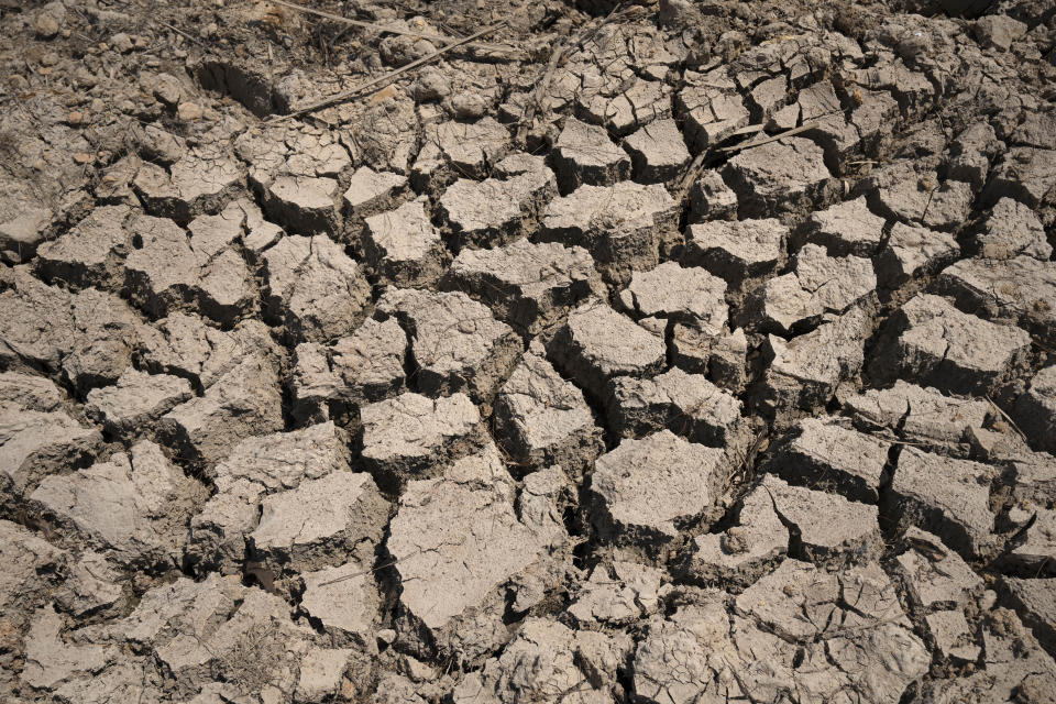 FILE - Cracked dry mud is seen in a community reservoir that ran nearly empty after its retaining wall started to leak and hot weather and drought conditions accelerated the loss of water Longquan village in southwestern China's Chongqing Municipality, Saturday, Aug. 20, 2022. The very landscape of Chongqing, a megacity that also takes in surrounding farmland and steep and picturesque mountains, has been transformed by an unusually long and intense heat wave and an accompanying drought. (AP Photo/Mark Schiefelbein, File)