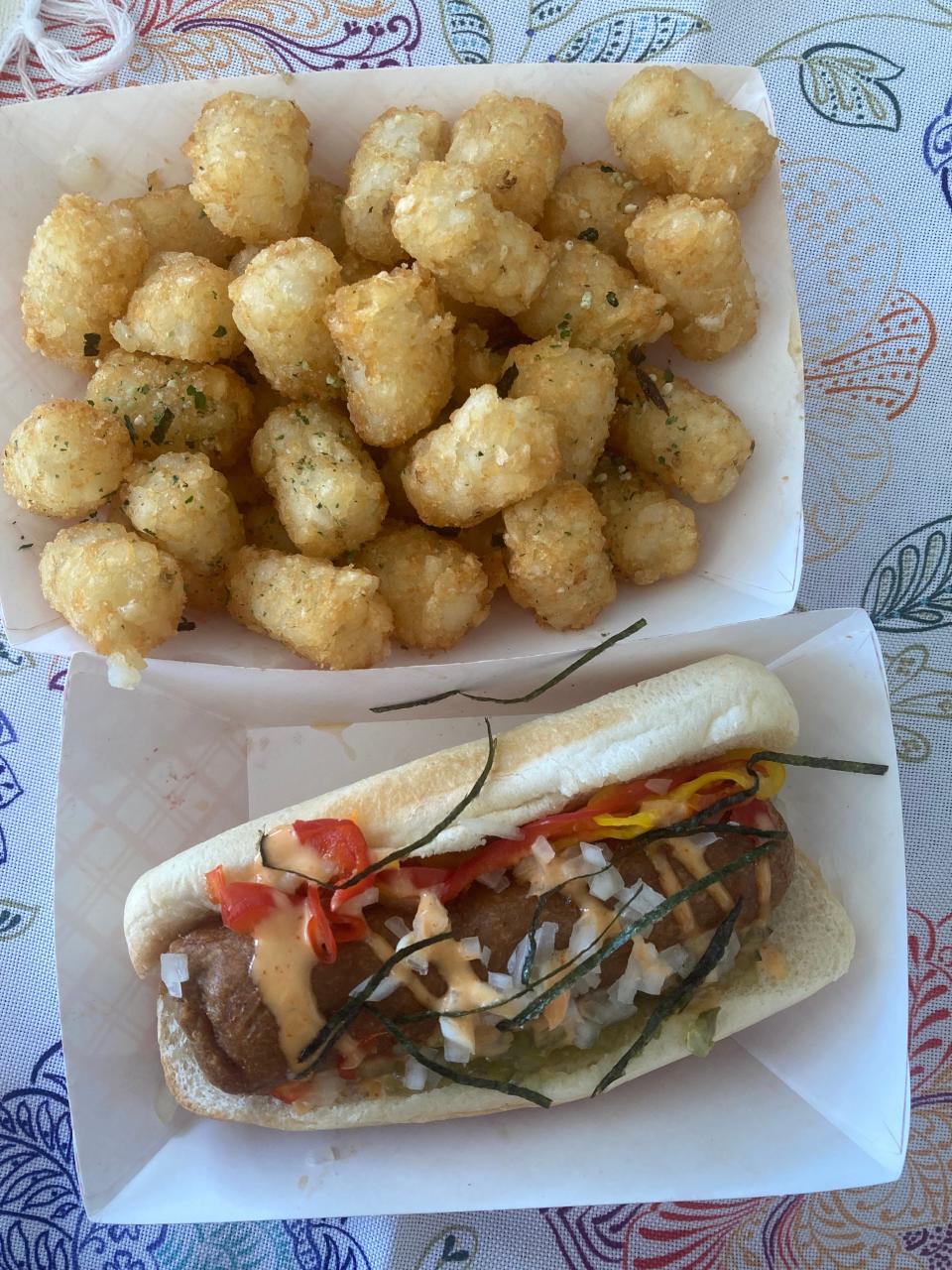 A vegan hot dog with a variety of toppings and tater tots from Sumo Dog.