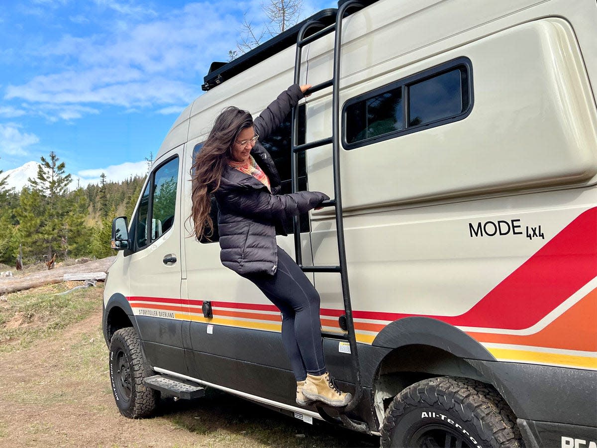 Ashley Probst hanging off the side of the camper van