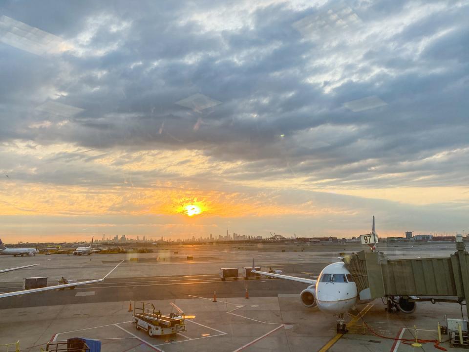 An airplane parked ini New Jersey as the sun rises on a cloudy morning