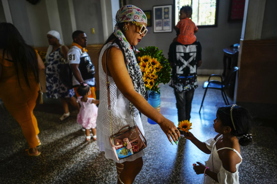 Una mamá y su hija se preparan para poner una ofrenda de flores a la Virgen de la Caridad del Cobre en su santuario en El Cobre, Cuba, el domingo 11 de febrero de 2024. (AP Foto/Ramón Espinosa)