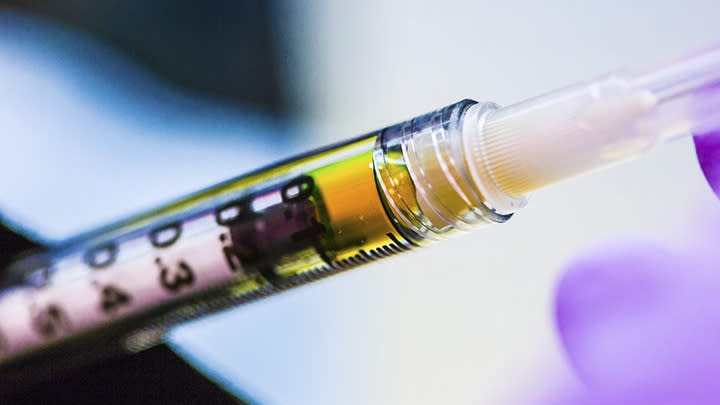  A syringe is seen with a tiny bit of yellowish liquid inside. 