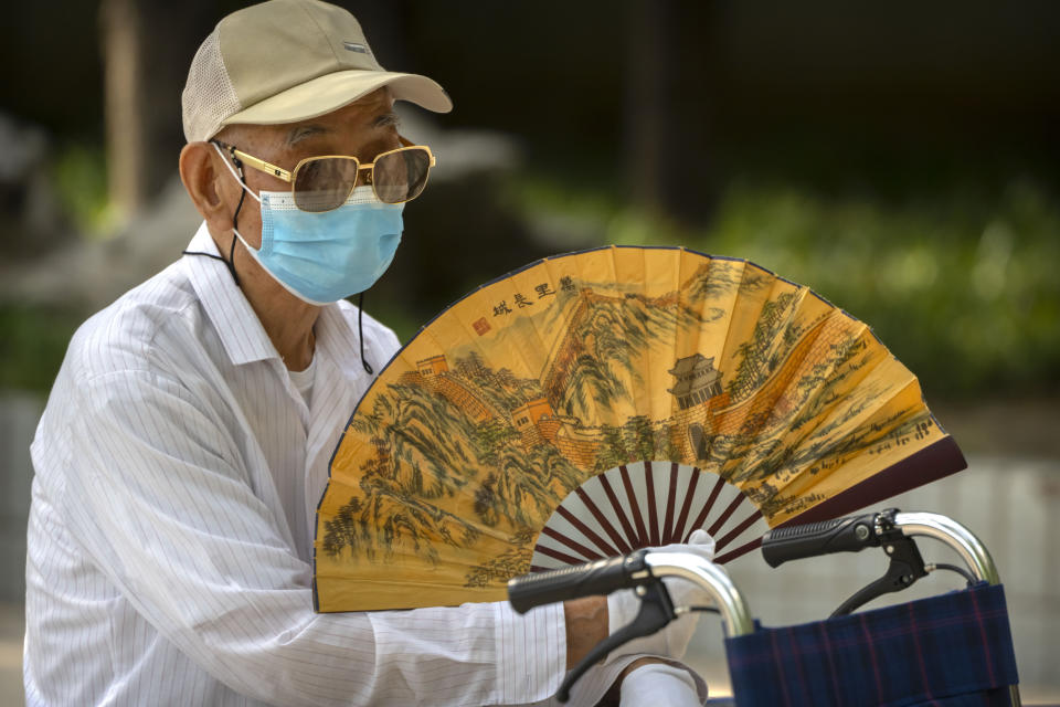 FILE - An elderly man wearing a face mask fans himself at a public park in Beijing, Friday, July 8, 2022. (AP Photo/Mark Schiefelbein, File)