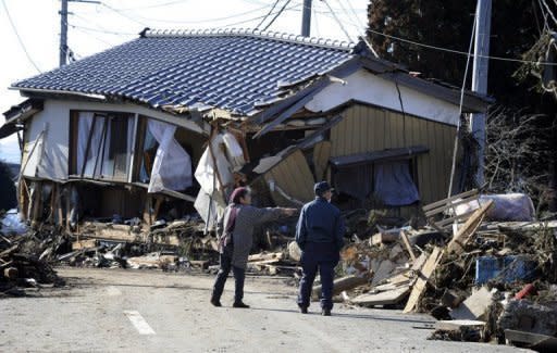 An elderly couple looks at a house destroyed by Friday's tsunami in Minamisoma, Fukushima Prefecture, on the northeastern coast of Japan's Honshu island, March 12, 2011. An explosion and feared meltdown at one of Japan's nuclear plants Saturday exposed the scale of the disaster facing the country after a massive quake and tsunami left 1,000 feared dead