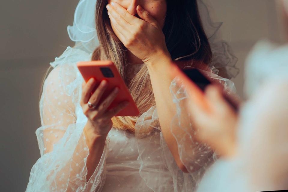<p>Getty</p> A stock image of a bride holding her phone