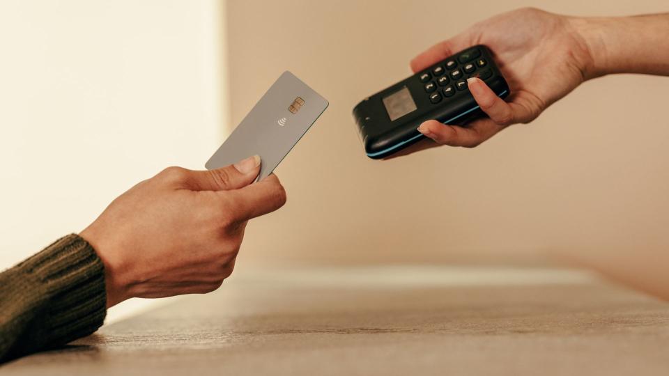 Woman's hands tapping credit card onto portable card reader