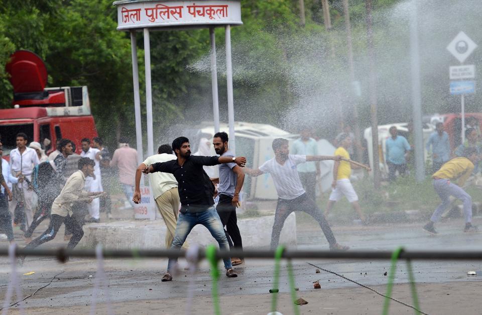 Supporters of Indian religious leader Gurmeet Ram Rahim Singh throw stones at security forces as they are sprayed with a water cannon in Panchkula on Aug. 25, 2017. (Photo: MONEY SHARMA via Getty Images)