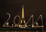 A reveller (unseen) writes "2014" with sparklers ahead of New Year's Eve, in front of the Eiffel Tower in Paris, December 30, 2013. Picture taken with long exposure. REUTERS/Benoit Tessier (FRANCE - Tags: CITYSCAPE SOCIETY ANNIVERSARY TPX IMAGES OF THE DAY)