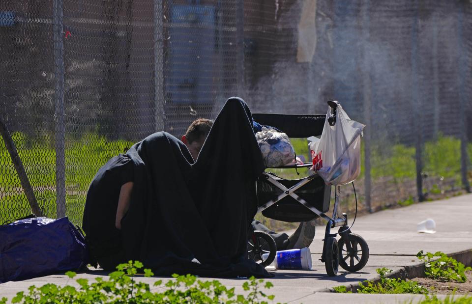 Homeless smoke underneath a jacket in the area called "The Zone." The Zone was downtown Phoenix's largest homeless encampment that the city court ordered to clear out in November.