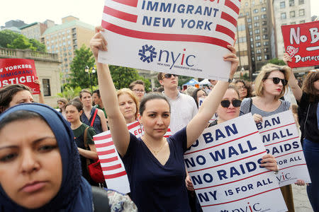 FILE PHOTO - Protesters hold signs against U.S. President Donald Trump's limited travel ban in New York City, U.S. on June 29, 2017. REUTERS/Joe Penney/File Photo