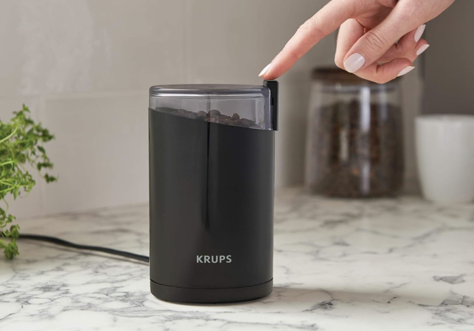 hand touching krups coffee grinder 